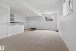 Carpeted lower level featuring recessed lighting, a built-in bar with open shelving, and a prominent window providing natural illumination - 