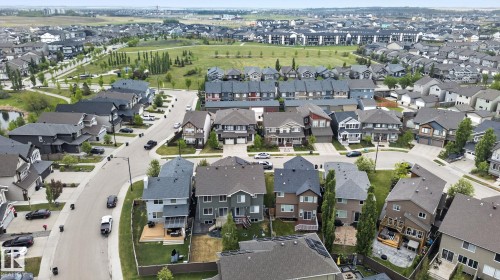 Aerial perspective showcasing a residential neighborhood with varied architectural styles, a central green space, and a pond - 3806 Powell Wynd, Edmonton, AB 