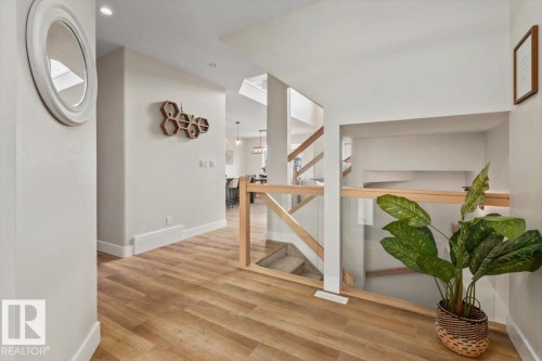 Hallway featuring wood-finish flooring, recessed lighting, and a contemporary glass and wood railing system - 45 Elwyck Gate, Spruce Grove, AB 