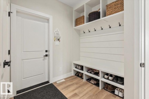 Dedicated mudroom featuring built-in storage, shiplap detailing, matte black coat hooks, and wood-finish flooring - 45 Elwyck Gate, Spruce Grove, AB 
