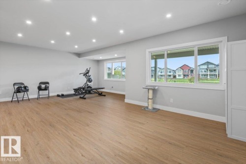 Spacious room featuring wood-finish flooring, recessed lighting, and light gray wall paint - 45 Elwyck Gate, Spruce Grove, AB 