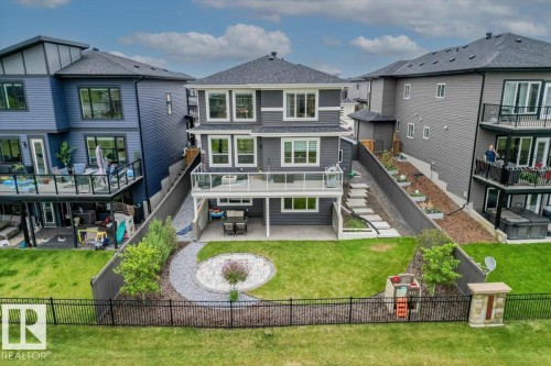 Spacious backyard featuring a manicured lawn, a circular paver patio, and a curved stone pathway - 45 Elwyck Gate, Spruce Grove, AB 