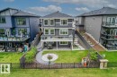 Spacious backyard featuring a manicured lawn, a circular paver patio, and a curved stone pathway - 45 Elwyck Gate, Spruce Grove, AB 