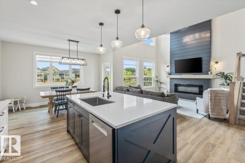 Open-concept living space with a central kitchen island featuring a stainless steel sink and a matte black faucet - 45 Elwyck Gate, Spruce Grove, AB 