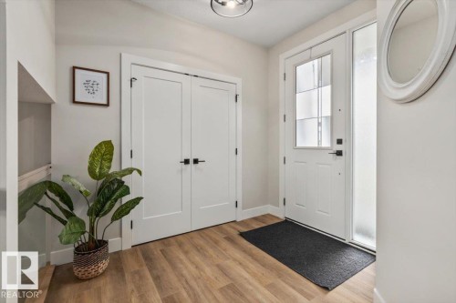 Foyer featuring wood-finish flooring, a contemporary ceiling light fixture, and a white entry door with frosted glass sidelight - 45 Elwyck Gate, Spruce Grove, AB 