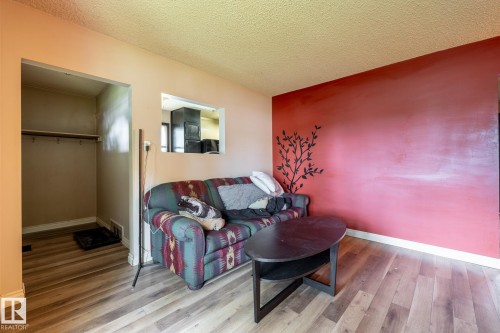 Living area featuring wood-finish flooring, a pass-through window, and textured ceiling - 5919 121 Avenue, Edmonton, AB 