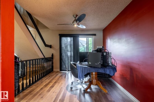 Upper-level landing featuring wood-finish flooring, a contemporary ceiling fan, and a vibrant accent wall - 5919 121 Avenue, Edmonton, AB 