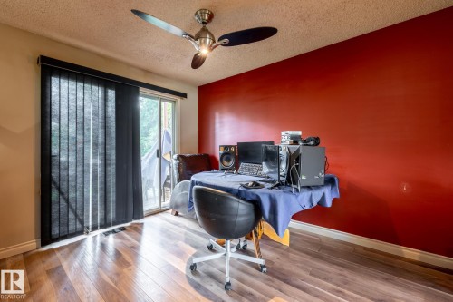 Room featuring wood-finish flooring, a ceiling fan with integrated lighting, and a sliding glass door with vertical blinds - 5919 121 Avenue, Edmonton, AB 