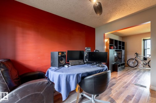 Versatile living space featuring wood-finish flooring and a bright accent wall - 5919 121 Avenue, Edmonton, AB 