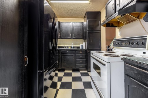 Kitchen featuring black cabinetry, checkered flooring, white electric range, and a black refrigerator - 5919 121 Avenue, Edmonton, AB 