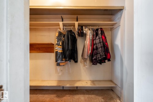 Recessed closet with painted interior, featuring a wood-finish hanging rod, upper shelving, and a lower shelf - 5919 121 Avenue, Edmonton, AB 