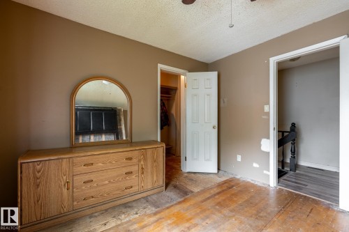 Interior room featuring wood-finish flooring, neutral wall paint, and a textured ceiling - 5919 121 Avenue, Edmonton, AB 