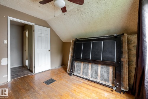 Room featuring wood-finish flooring, a ceiling fan with light fixture, and a sloped ceiling - 5919 121 Avenue, Edmonton, AB 