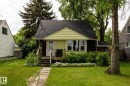 Charming single-story residence featuring light yellow siding with dark brown accents and a dark shingle roof - 5919 121 Avenue, Edmonton, AB 