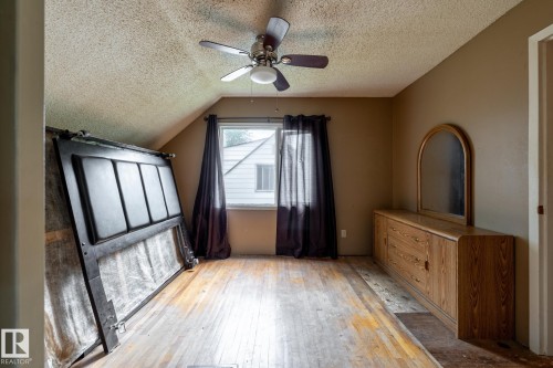 Room featuring sloped ceilings, a window with dark drapes, and wood-finish flooring - 5919 121 Avenue, Edmonton, AB 