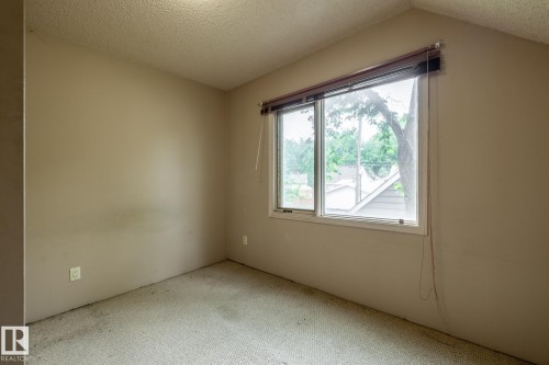 Room with a window offering exterior scenery, wall-to-wall carpeting, and sloped ceiling detail - 5919 121 Avenue, Edmonton, AB 