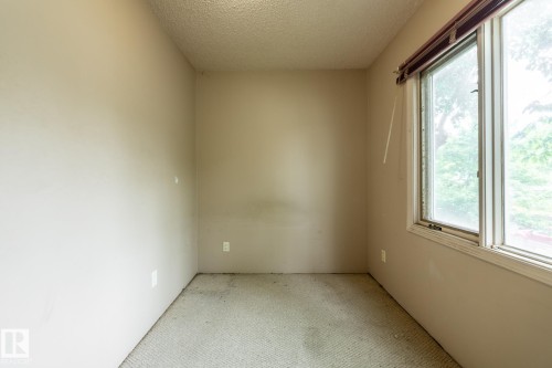 Room with an expansive window offering natural light, textured ceiling, and neutral-toned carpeting - 5919 121 Avenue, Edmonton, AB 