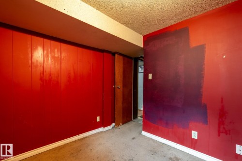 Interior room featuring a textured ceiling, red wall paneling, and a wood-finish door - 5919 121 Avenue, Edmonton, AB 