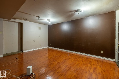 Room featuring wood-finish flooring, track lighting, and a neutral color palette - 5919 121 Avenue, Edmonton, AB 