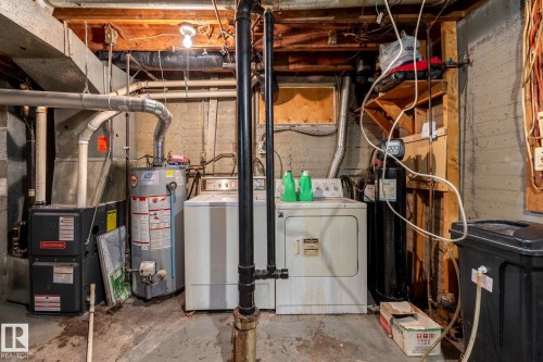 Basement utility area featuring a hot water heater, furnace, and laundry appliances - 5919 121 Avenue, Edmonton, AB 