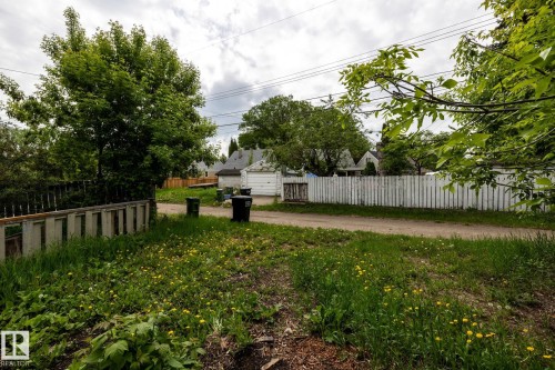 Gravel alleyway bordering a grass and dirt area with dappled light - 5919 121 Avenue, Edmonton, AB 