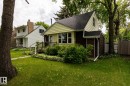 Charming residence featuring a light yellow facade, dark brown siding, and a prominent front porch - 5919 121 Avenue, Edmonton, AB 