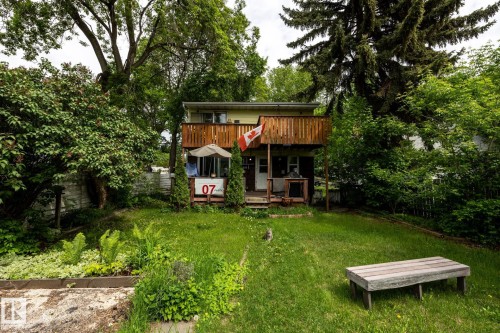 Two-story exterior with a wood-plank upper deck and ground-level patio - 5919 121 Avenue, Edmonton, AB 