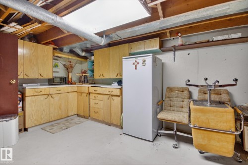 Kitchenette featuring wood-finish cabinetry, white countertops, and white flooring - 9243 74 Street, Edmonton, AB 