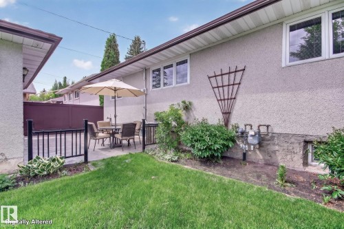 Private patio area with black metal railing, paver stone surface, and an adjacent landscaped garden bed - 9243 74 Street, Edmonton, AB 