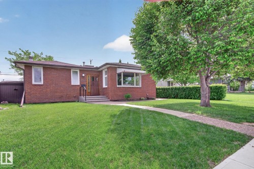 Brick exterior featuring a front lawn and a mature tree - 9243 74 Street, Edmonton, AB 