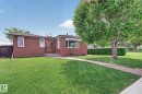 Brick exterior featuring a front lawn and a mature tree - 9243 74 Street, Edmonton, AB 