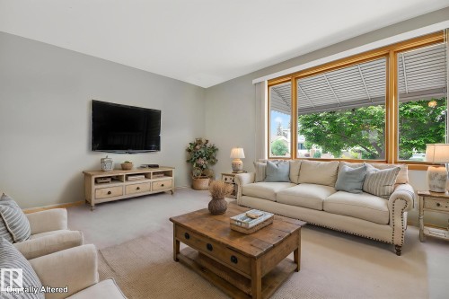 Spacious living area featuring light-toned wall paint and large windows with natural wood trim - 9243 74 Street, Edmonton, AB 