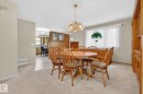Dining area featuring a decorative chandelier, light-toned carpeting, and a built-in wall unit with wood-finish cabinetry - 9243 74 Street, Edmonton, AB 
