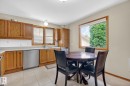 Kitchen featuring wood cabinetry, light countertops, a stainless steel dishwasher, and tile flooring - 9243 74 Street, Edmonton, AB 