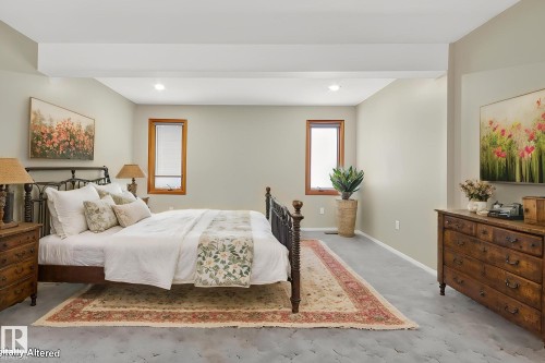 Spacious room featuring light gray walls, two windows with wood trim, recessed lighting, and a soft gray flooring - 9243 74 Street, Edmonton, AB 