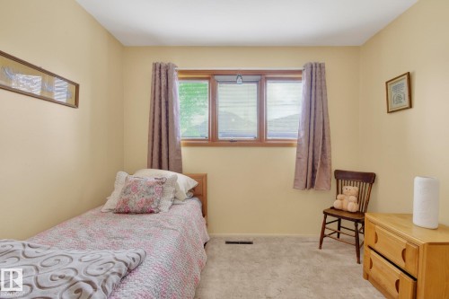 Interior space featuring a window with wood trim, neutral wall paint, and light-colored carpet flooring - 9243 74 Street, Edmonton, AB 
