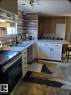 Kitchen featuring new white cabinetry with black hardware, double basin sink with black faucet, wood-finish backsplash, and light-toned countertops - 14 Willowdale Drive, Edmonton, AB 