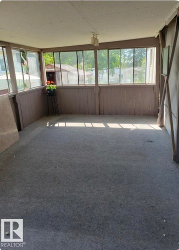 Enclosed sunroom featuring a paneled wood half-wall, multiple window panes, and a mounted ceiling light fixture - 14 Willowdale Drive, Edmonton, AB 