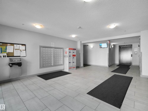 Lobby featuring large format tile flooring, multiple flush-mount ceiling lights, and wall-mounted mailboxes - 406 11820 22 Avenue, Edmonton, AB 