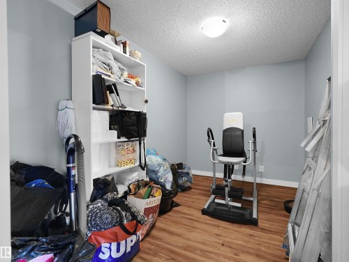 Interior room featuring wood-finish flooring, light blue painted walls, a white ceiling, and a flush-mount ceiling light - 406 11820 22 Avenue, Edmonton, AB 