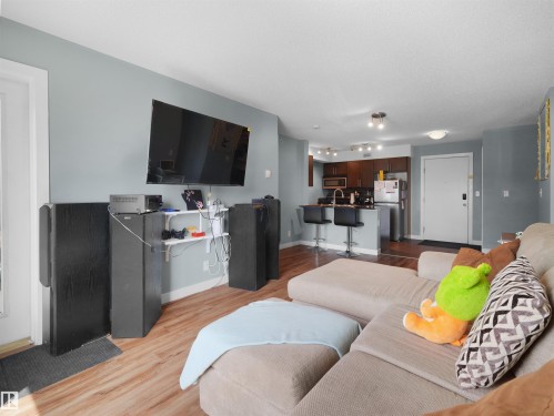 Open-concept living area featuring wood-finish flooring, light gray walls, and recessed lighting - 406 11820 22 Avenue, Edmonton, AB 
