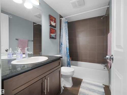 Bathroom featuring a dark wood-finish vanity with a white oval undermount sink and dark countertop - 406 11820 22 Avenue, Edmonton, AB 