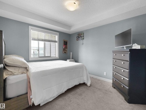 Tray ceiling bedroom with light blue walls and neutral carpet flooring - 406 11820 22 Avenue, Edmonton, AB 