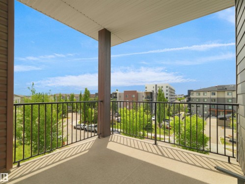 Private balcony with a concrete surface, black metal railings, and a wood-finish support column - 406 11820 22 Avenue, Edmonton, AB 