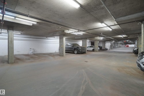 Underground parking garage featuring concrete flooring, concrete support columns, and overhead fluorescent lighting - 406 11820 22 Avenue, Edmonton, AB 