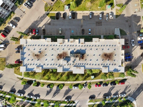Multi-unit building featuring expansive roofline, integrated parking areas, and surrounding green spaces - 406 11820 22 Avenue, Edmonton, AB 