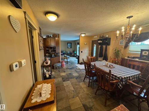 Dining area featuring slate-style tile flooring and a multi-arm chandelier - 4502 55 Avenue, Vegreville, AB 