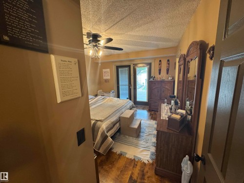 Room featuring wood-finish flooring, a ceiling fan with integrated lighting, and a glass-paneled exterior door - 4502 55 Avenue, Vegreville, AB 