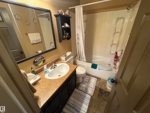 Bathroom featuring a vanity with a laminate countertop, integrated sink, and dark wood-finish cabinetry - 4502 55 Avenue, Vegreville, AB 