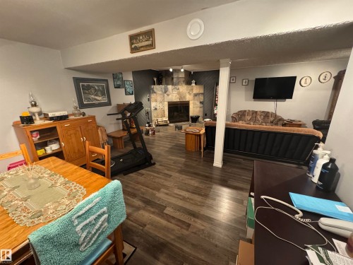 Spacious recreation room featuring wood-finish flooring, a stone-clad fireplace, and recessed lighting - 4502 55 Avenue, Vegreville, AB 